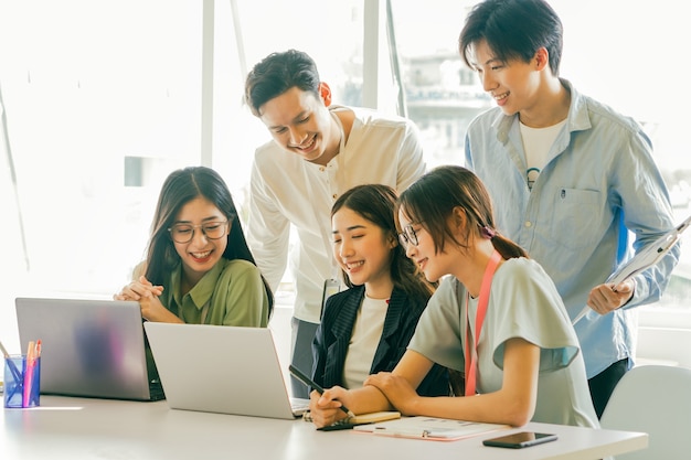 Photo asian business people are looking at their business plans together on their laptop screens